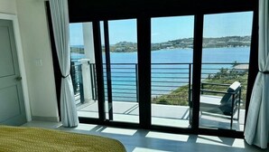 A bedroom with a large sliding glass door leading to a balcony with a view of the sea. - Luxury Villa in Cabrita Point- Sky View Villa with Pickleball & Basketball Court (ST THOMAS)