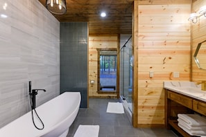 A modern bathroom with a freestanding bathtub, a wooden vanity, and a glass shower enclosure.