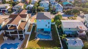 Un quartier résidentiel en bord de mer, avec des maisons, une piscine et une plage en arrière-plan.