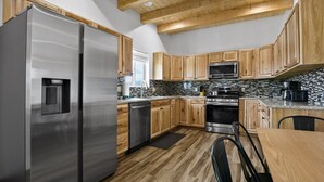 Una cocina moderna con electrodomésticos de acero inoxidable, armarios de madera y salpicadero de piedra.