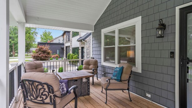 A covered porch with wooden flooring, two chairs, a table, and a window with blinds. - Trail Side in the Heart of Winona Lake (Winona Lake)