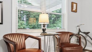 Two brown leather chairs, a small table with a lamp, and a bicycle leaning against the wall. - Trail Side in the Heart of Winona Lake (Winona Lake)