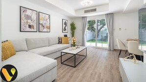 A modern living room with a grey sofa, a coffee table, and artwork on the walls. - Vogue | Springs Villa Emirates Hills close to Mall of the Emirates | Ski Dubai (Dubai)