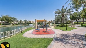 A park with exercise equipment, a water body, and a pathway. - Vogue | Springs Villa Emirates Hills close to Mall of the Emirates | Ski Dubai (Dubai)