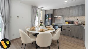A modern kitchen with grey cabinets, a built-in oven, and a microwave. - Vogue | Springs Villa Emirates Hills close to Mall of the Emirates | Ski Dubai (Dubai)