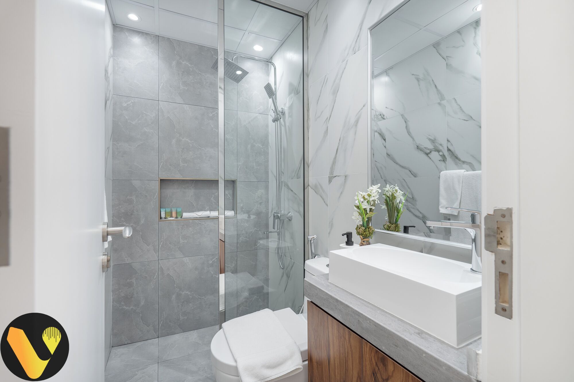 A modern bathroom with a glass-enclosed shower, a white sink, and a marble backsplash.