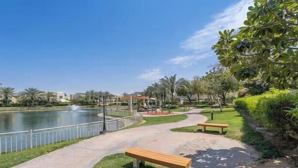 A park with a pond, benches, a pathway, and palm trees. - Vogue | Springs Villa Emirates Hills close to Mall of the Emirates | Ski Dubai (Dubai)