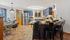 Une cuisine moderne avec des meubles de couleur bleue, un réfrigérateur en acier inoxydable et une table à manger en bois, assortie de chaises.