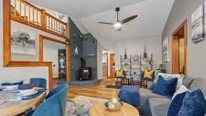 Un vaste salon comprenant un coin repas, un escalier en bois et un ventilateur de plafond.