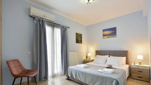 A hotel room with a bed, a chair, a nightstand, and a painting on the wall. - Corfu SeaTy Apartment (Corfu)