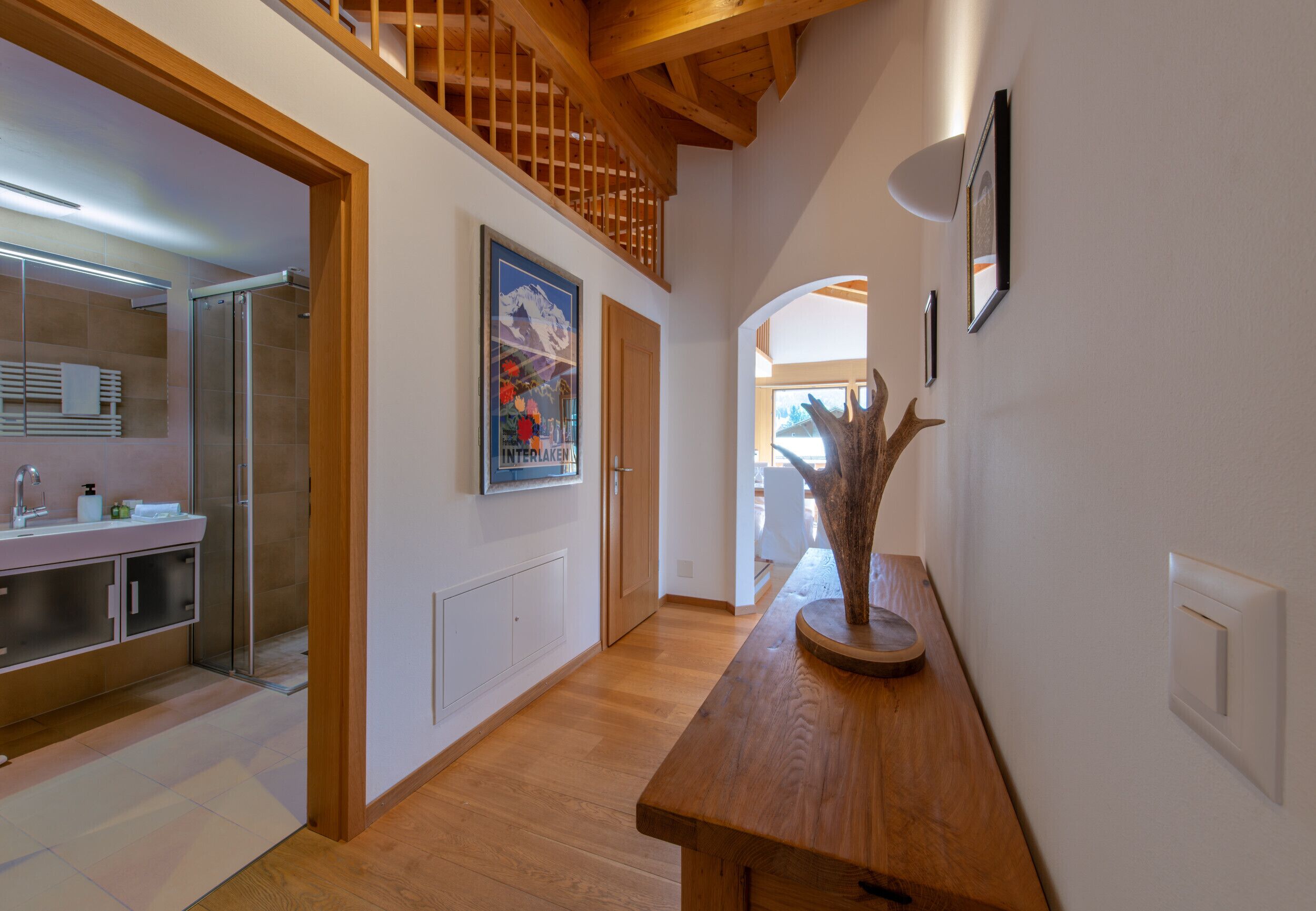 A modern interior with a wooden bench, a glass shower, and a framed picture on the wall.