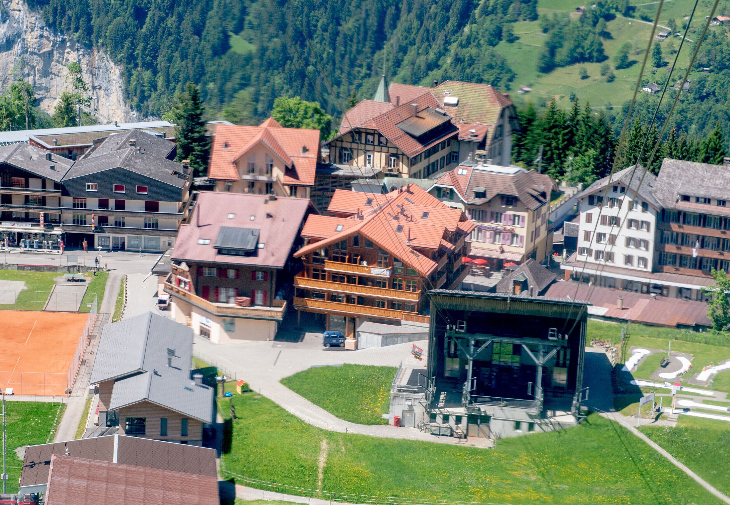 A traditional European-style hotel with multiple buildings, a central courtyard, and a mountain backdrop.