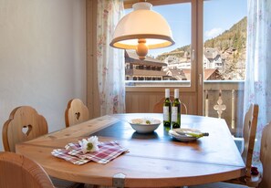 A wooden dining table with a bowl, two wine bottles, and a placemat.