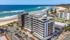 Ein Hotel an der Küste mit mehreren Etagen, Balkonen und Blick auf den Strand.