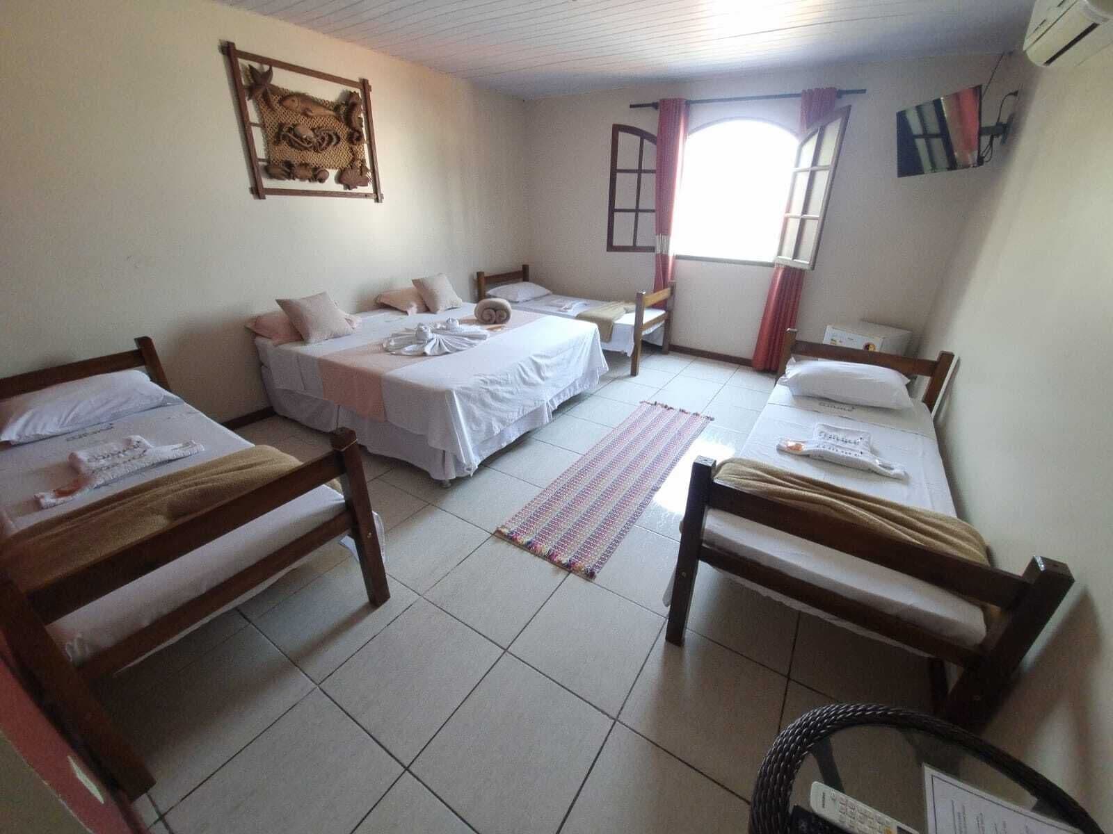 A room with three beds, a window, and a wall-mounted artwork.