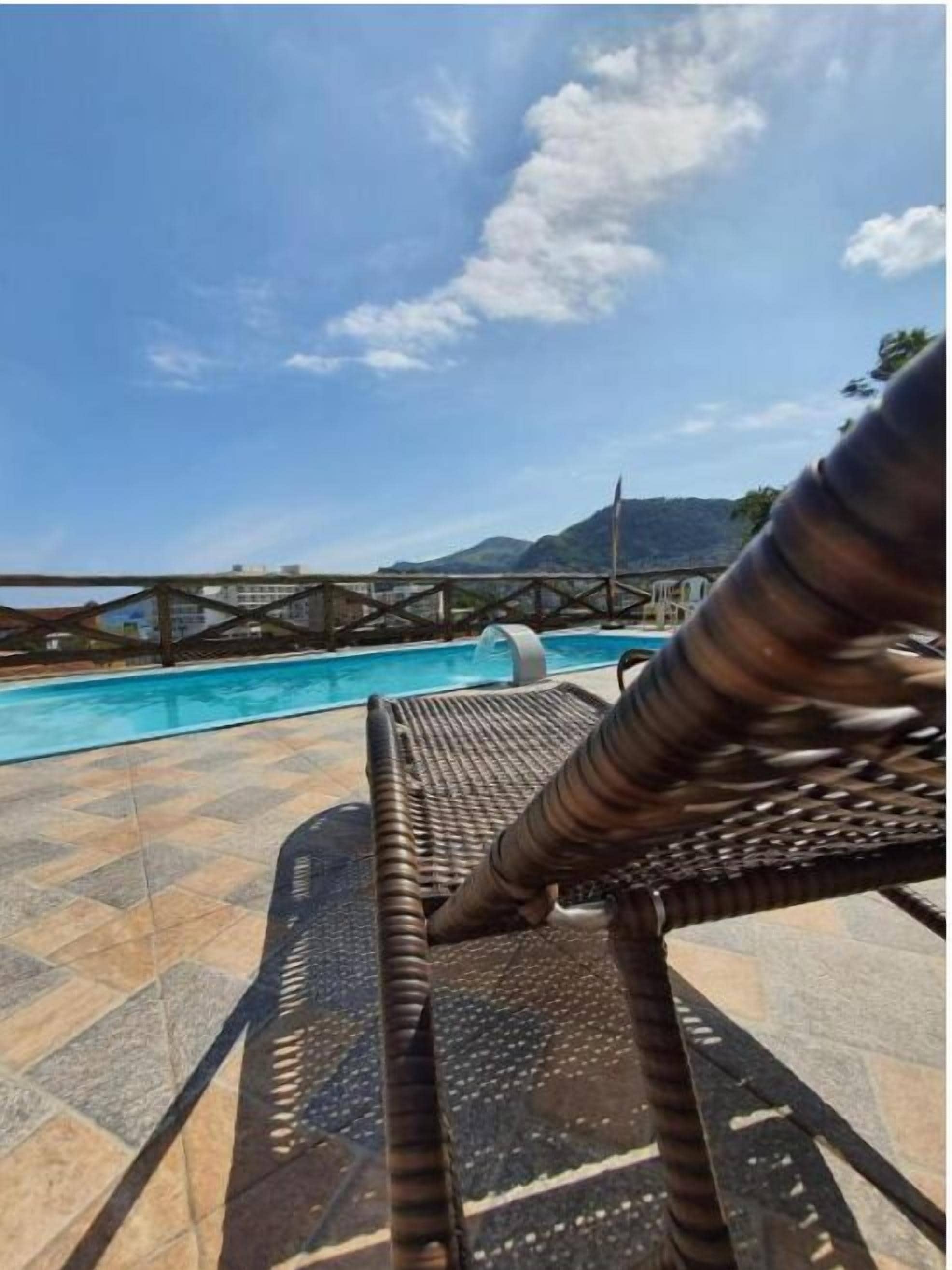 Una piscina al aire libre, sombrillas, sillones reclinables de piscina