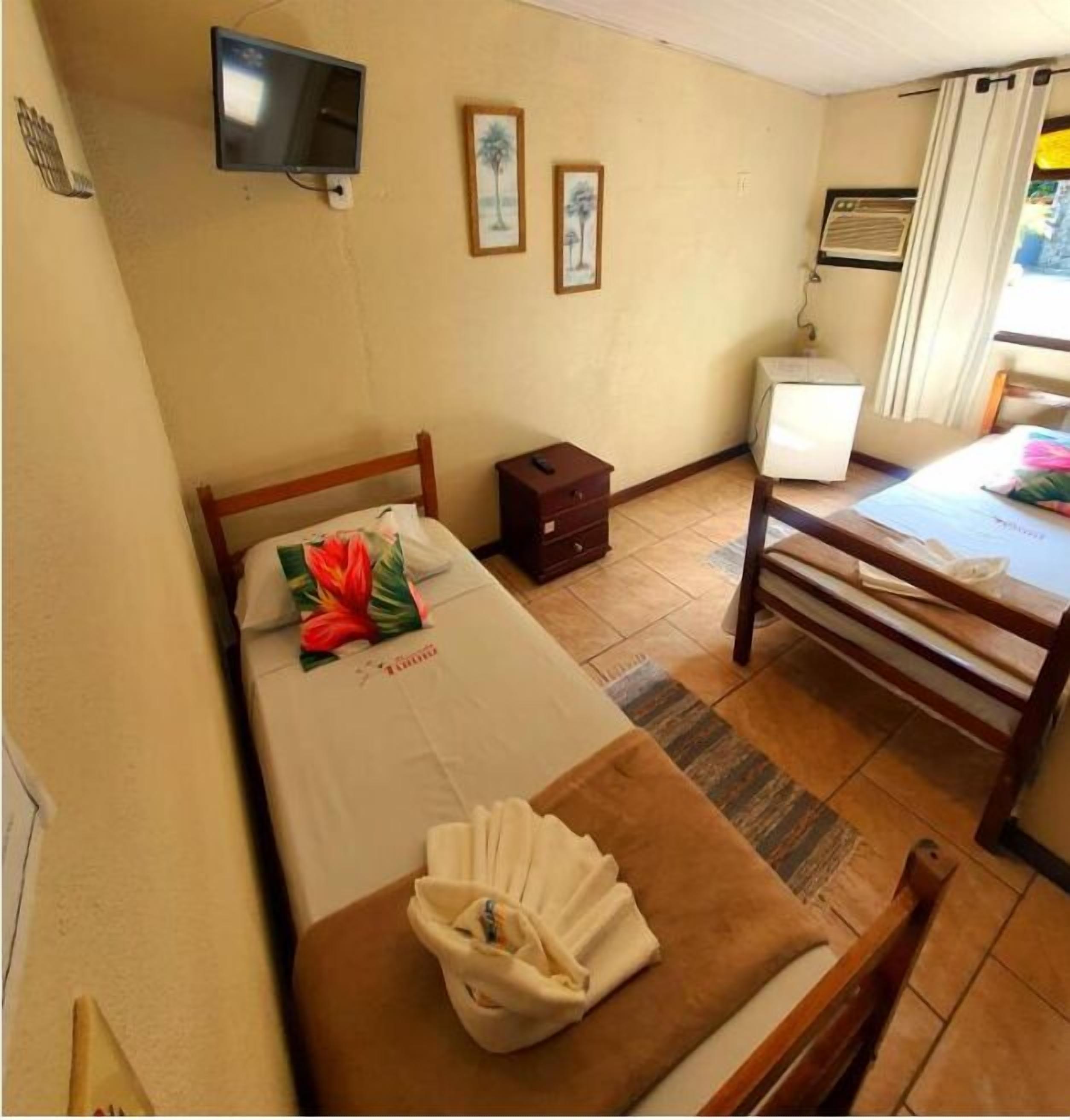 A hotel room with a bed, a TV, a small table, and a chair.
