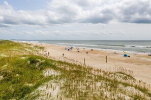 A beach with dunes, people, and tents.