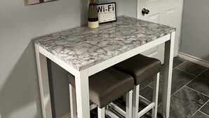 Una mesa de comedor con cubierta de mármol, dos bancos, un florero con plantas secas y un cartel de Wi-Fi.