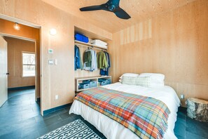 Relax in this cozy retreat with a large bed, ceiling fan, and shelving unit.