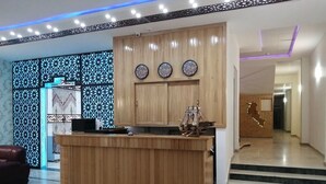 A modern kitchen with wooden cabinets and a central island, a decorative wall with geometric patterns, and a staircase leading to another area. - Hotel Salsabil Naoui (Djelfa)