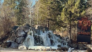 A waterfall with a sign reading "SUNRIVER" in a forested area.
