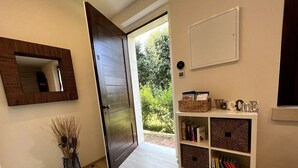 A hallway with a wooden door, a mirror, a bookshelf, and a vase with dried plants. - Cozy and bright apartment with a garden: pets allowed (Lombardia)