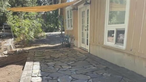 Un patio de piedra con un muro de piedra y un toldo amarillo.