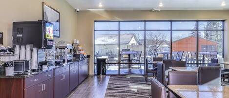 A modern kitchen with a coffee station, large windows, and a view of the outside.