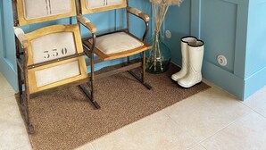 Una habitación con un banco de madera, un estante en la pared, un cartel decorativo y un jarrón con plumas de plumas.
