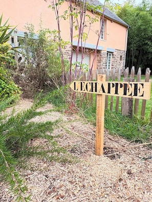 A wooden sign with the word 'LECHAPPEE' in front of a stone building with a wooden fence. - L'échappée Le Giré Vacation Rental near Granville (Hudimesnil)