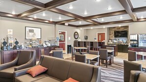 Een hotel lobby met zitgedeeltes, een bar en een keuken in de achtergrond.