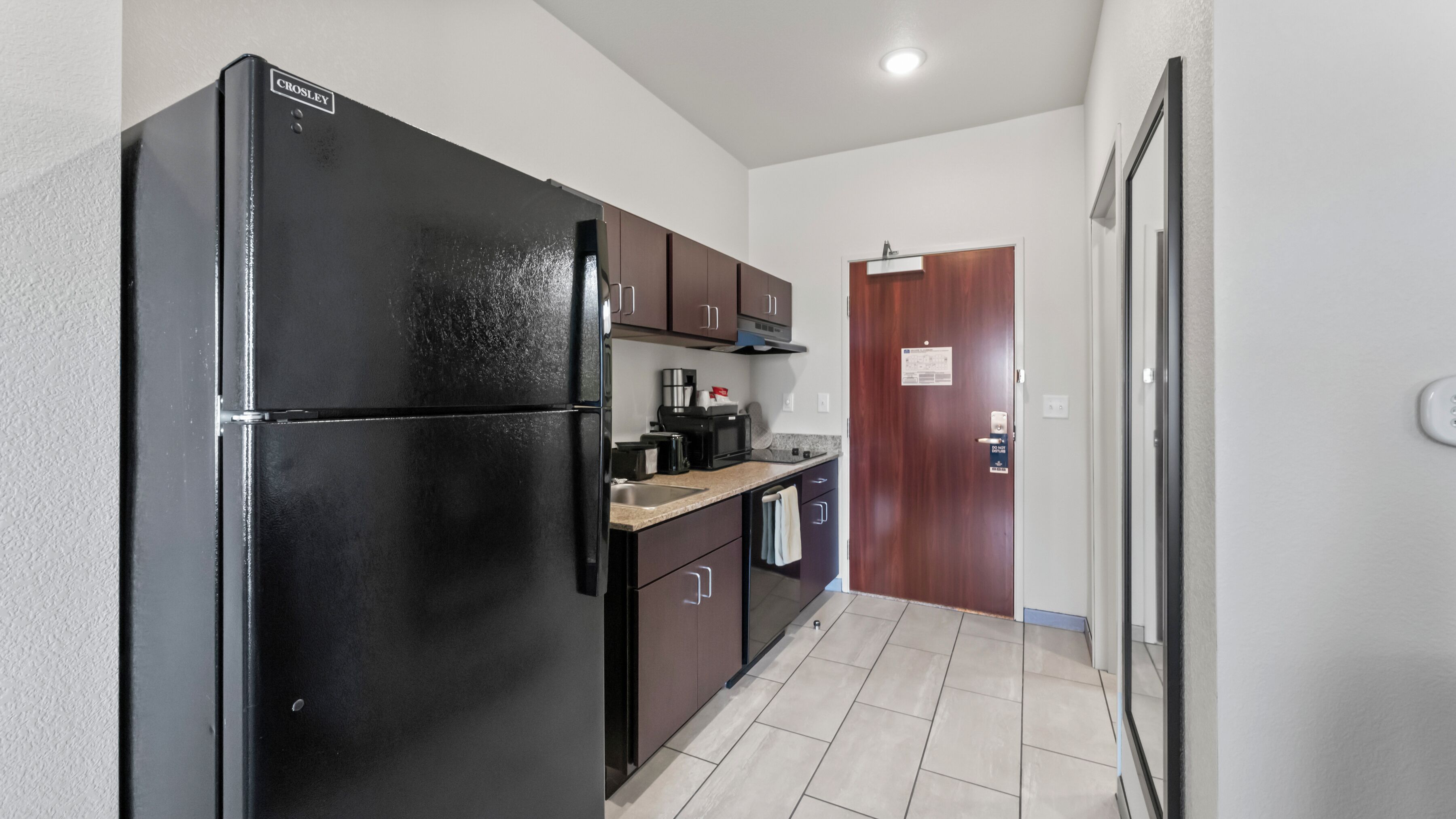 Una cocina compacta con un refrigerador negro, un microondas y una cafetera sobre la encimera.