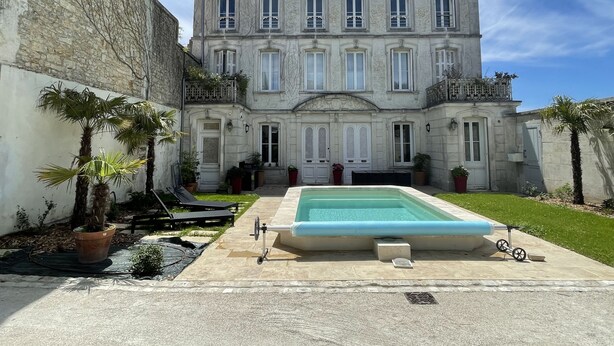 A large, historic building with a central courtyard, a swimming pool, and a stone wall. - Hôtel Particulier Hyper Centre de Rochefort (Rochefort)