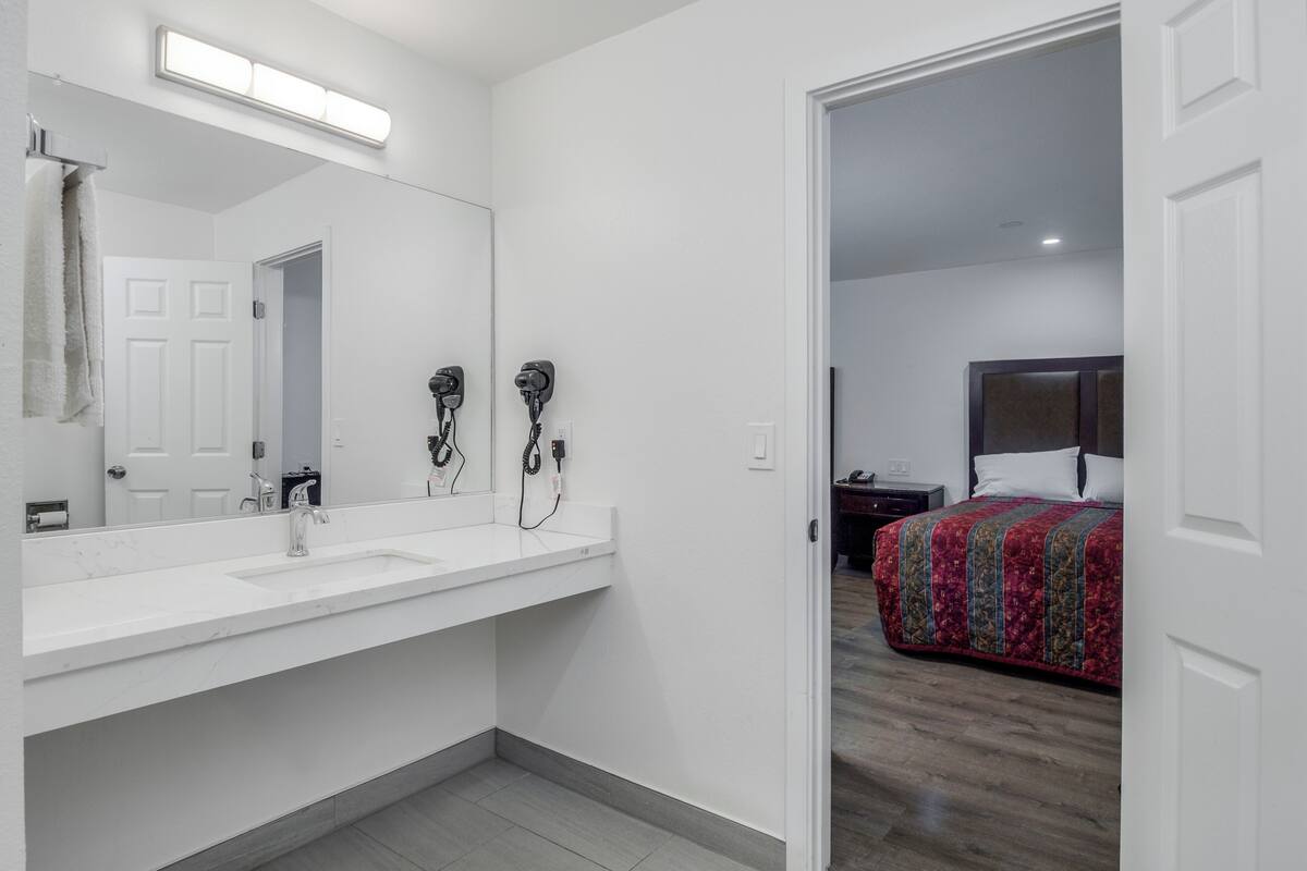 Un baño moderno con un espejo grande, dos secadores de pelo y un lavamanos blanco.