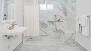 A modern bathroom with a marble shower wall, a white sink, and a towel rack. - The Alameda Motel San Jose (San Jose)