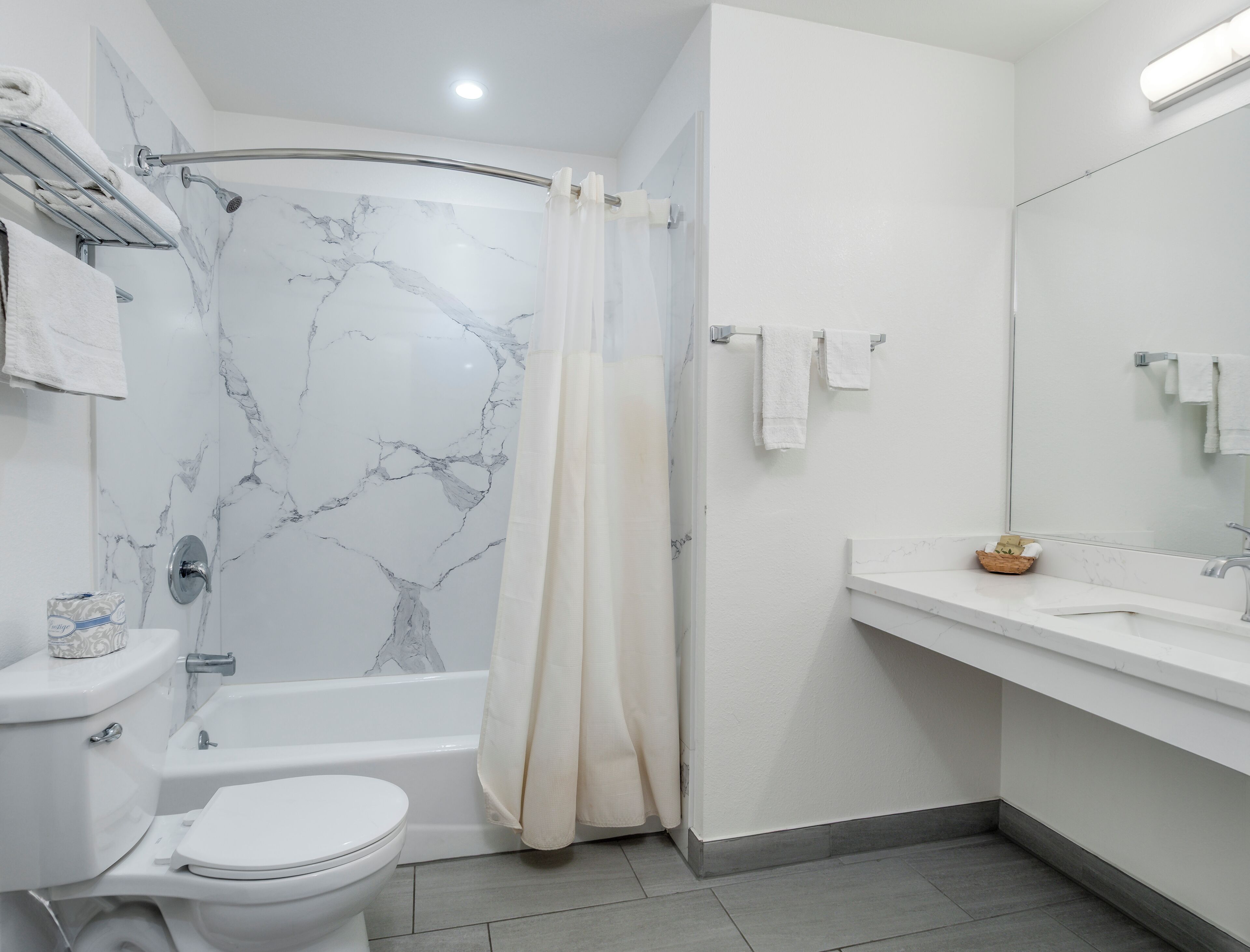 A bathroom with a marble shower, a toilet, a bathtub, and a sink with a mirror.