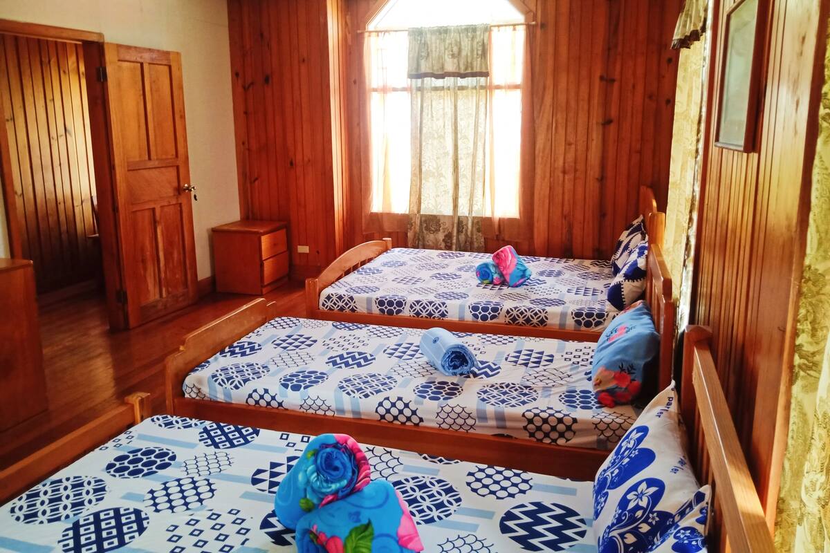 Ein Zimmer mit zwei Holzbetten, einem Schrank aus Holz und einem kleinen Nachttisch.