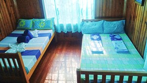 Two single beds with blue and green bedding, wooden headboards, and a window with a white curtain. - ROOMS AT AN AMERICAN-STYLE CABIN (Sagada)