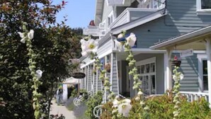 Uma casa tradicional com varanda, um caminho e um jardim com flores brancas.