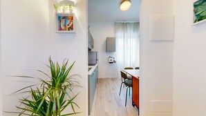 A modern kitchen with a dining area, a potted plant, and a painting on the wall. - Four stops from the center of Milan, you will have all the comforts of home! (Milano)