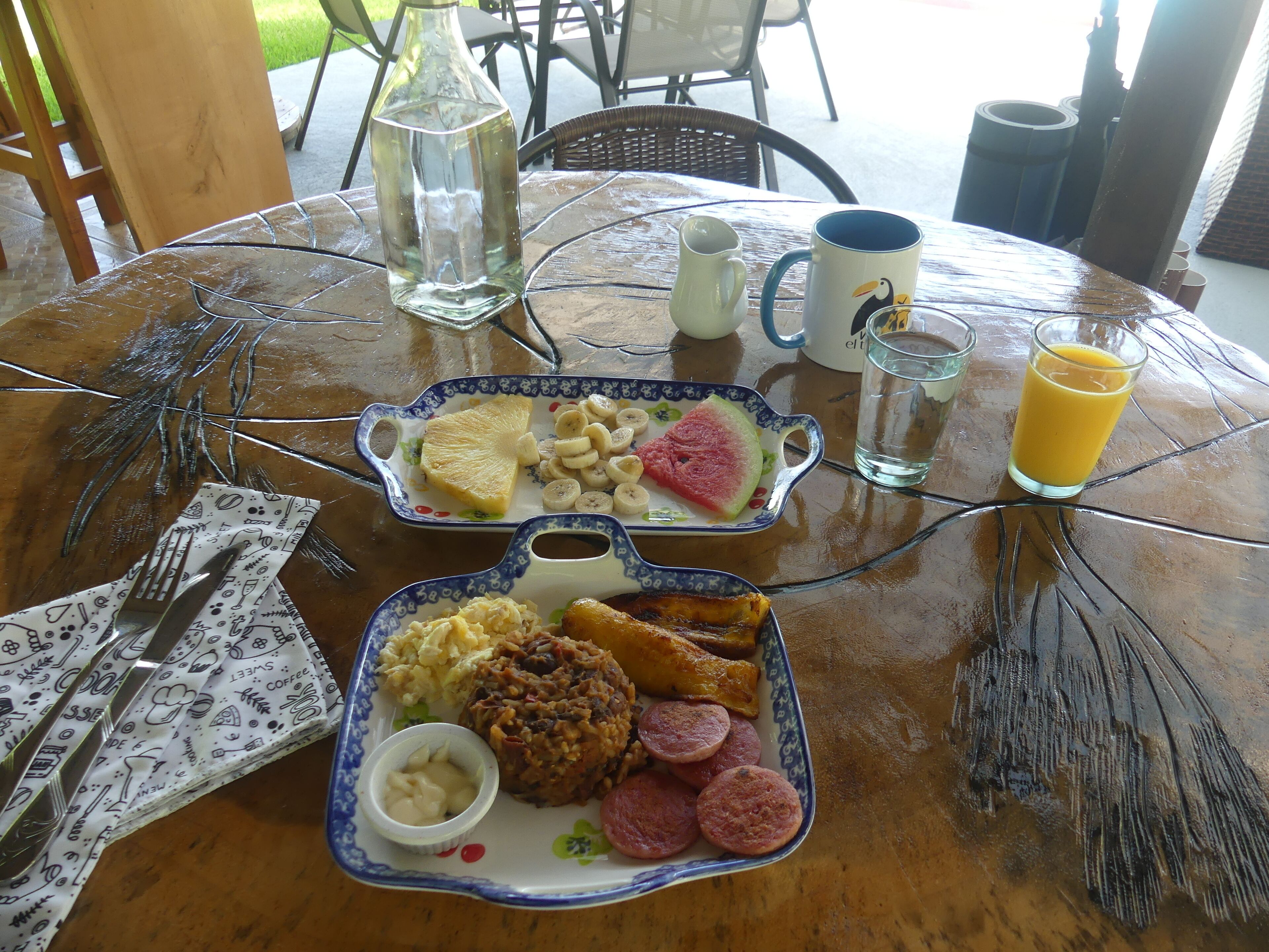 Una tavola per la colazione con due piatti di cibo, un bicchiere di succo d'arancia e una tazza.