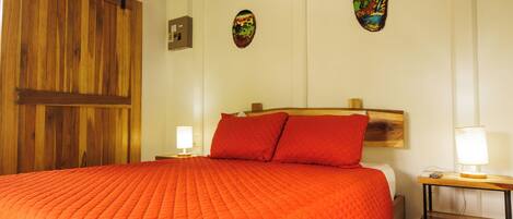 A bedroom with a large bed, wooden headboard, two bedside lamps, and a wooden door.