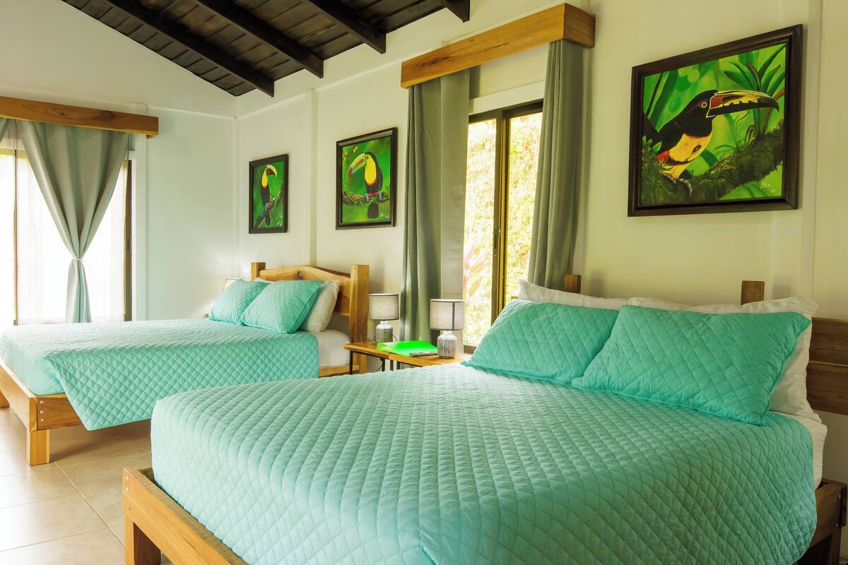 A hotel room with two beds, a wooden headboard, a nightstand, and a window with curtains.