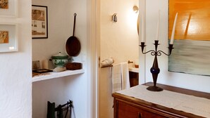 A room with a wooden dresser, a hanging lamp, a painting, and a door leading to another room. - Monte Alentejano Perto de Montemor-o-novo (Foros do Baldio)