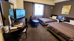 Habitación de hotel con cama, escritorio con computadora, una silla y televisión.