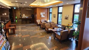 Un vestíbulo de hotel con mostrador de recepción, zona de estar y amplios ventanales.