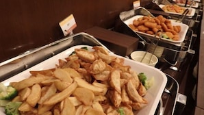 Un bufé con distintos alimentos, incluyendo papas fritas, verduras y otros platos.