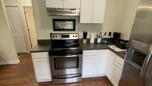 Una cocina con armarios blancos, una estufa negra y un refrigerador de acero inoxidable.