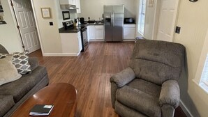 Una sala de estar moderna con un sillón gris, una mesa de centro de madera y un ventilador de techo.